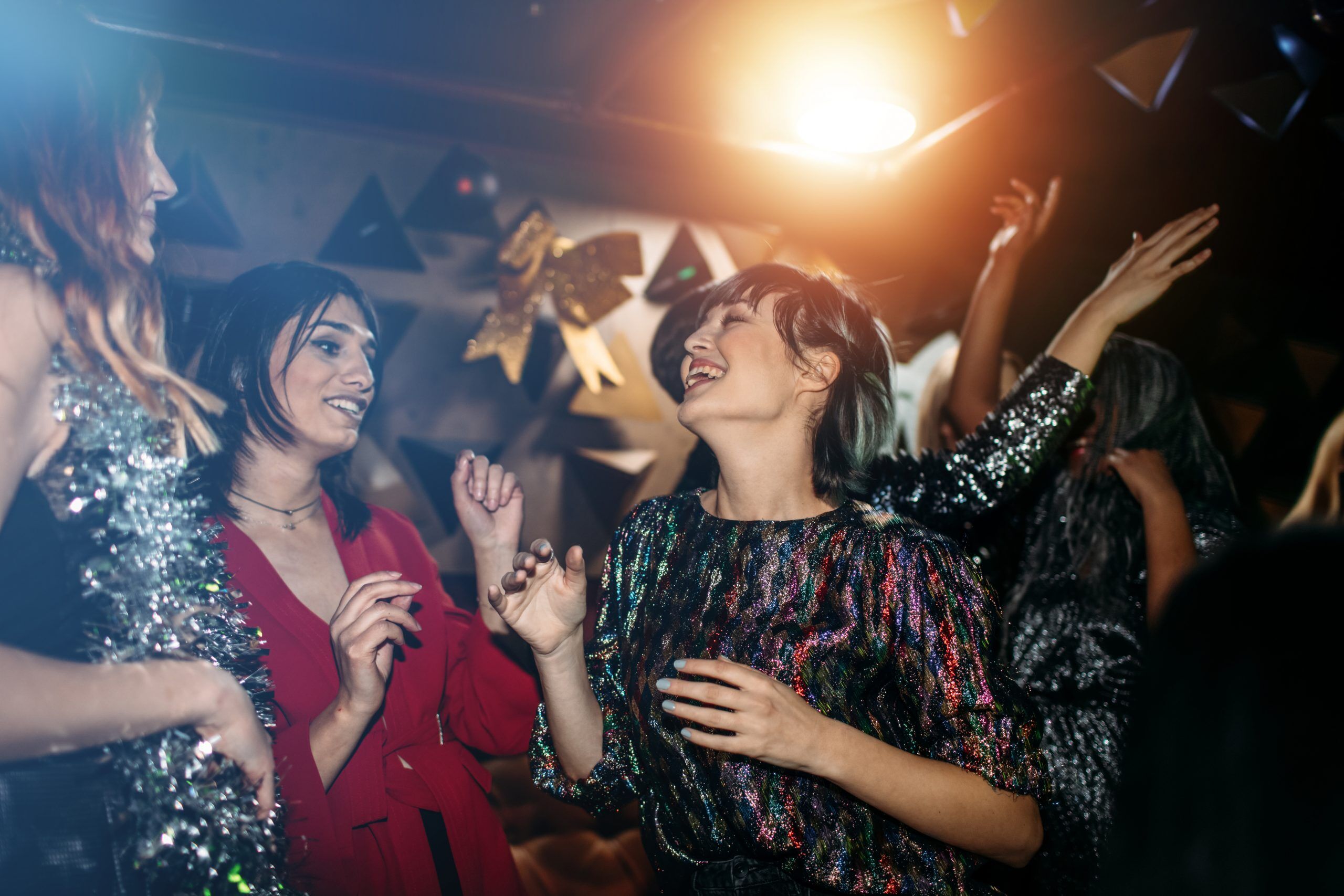 Group of young LGBTQ+ people smiling and dancing at a party.
